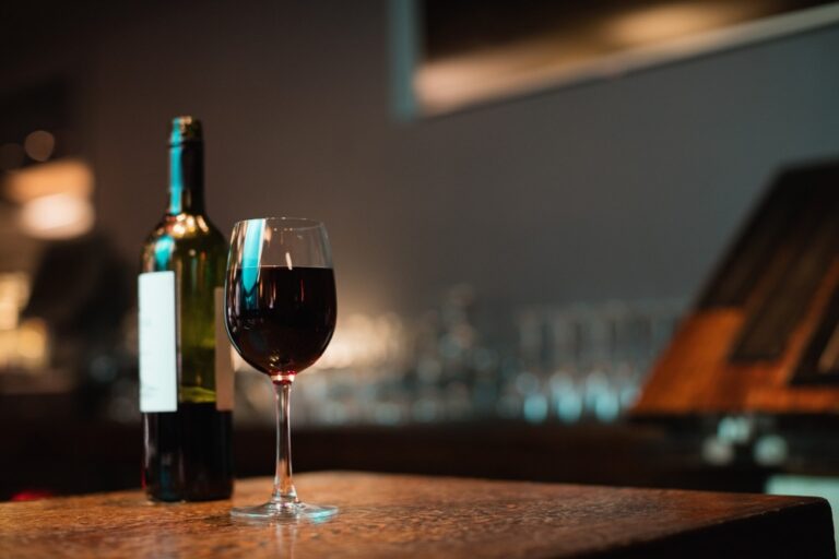 verre de vin rouge et bouteille sur un comptoir de bar