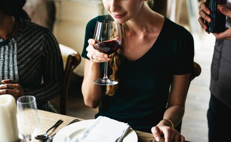 Femme dégustant du vin rouge dans un restaurant chic